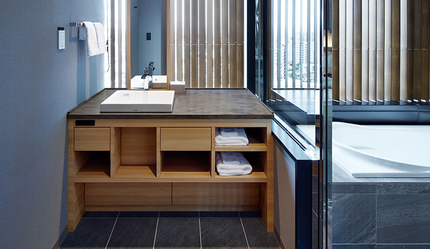 プレミアムルームでは、熊本市街地の景色を見下ろす窓に面してガラス張りのバスルームと洗面化粧台が配置されている。